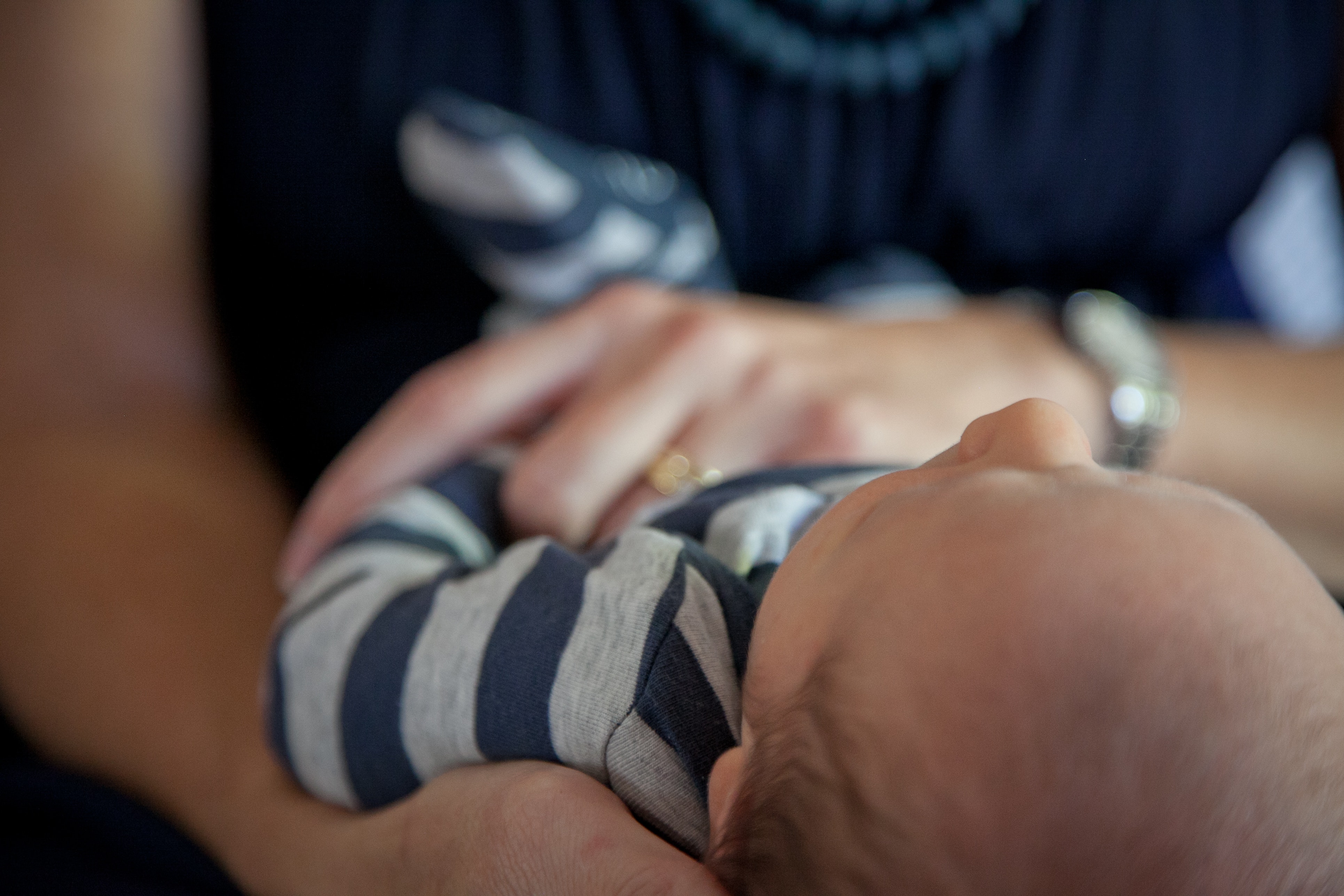 Newborn baby with striped onesie laying on mom's lap