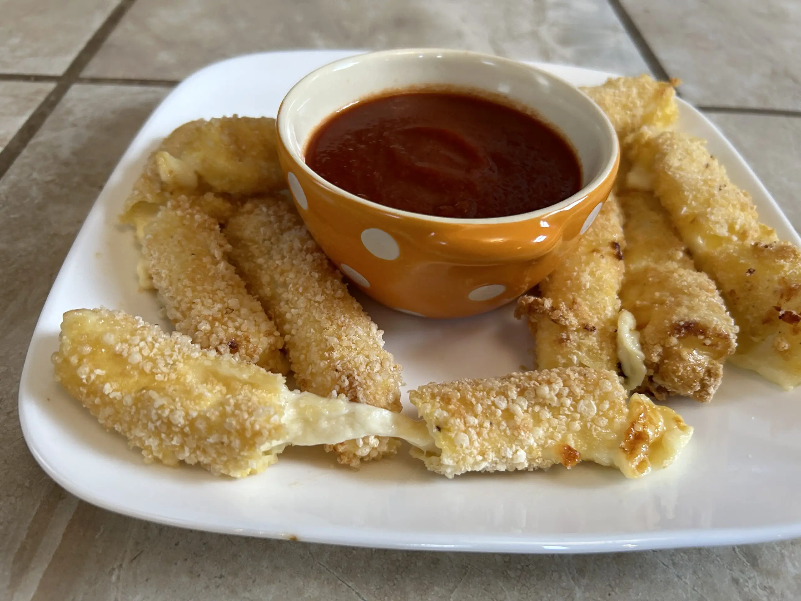 Plate of gluten free mozarella sticks with dipping sauce